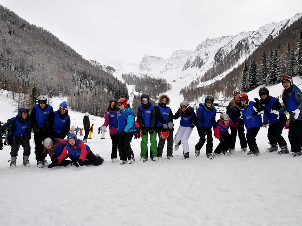 Gruppe in lockerer Aufstellung auf der Piste, einige knien im Schnee.